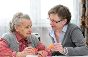 a young lady talking to an old lady with jigsaw pieces in their hands