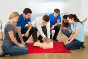 a picture of people doing cpr for a first aid at work course near me